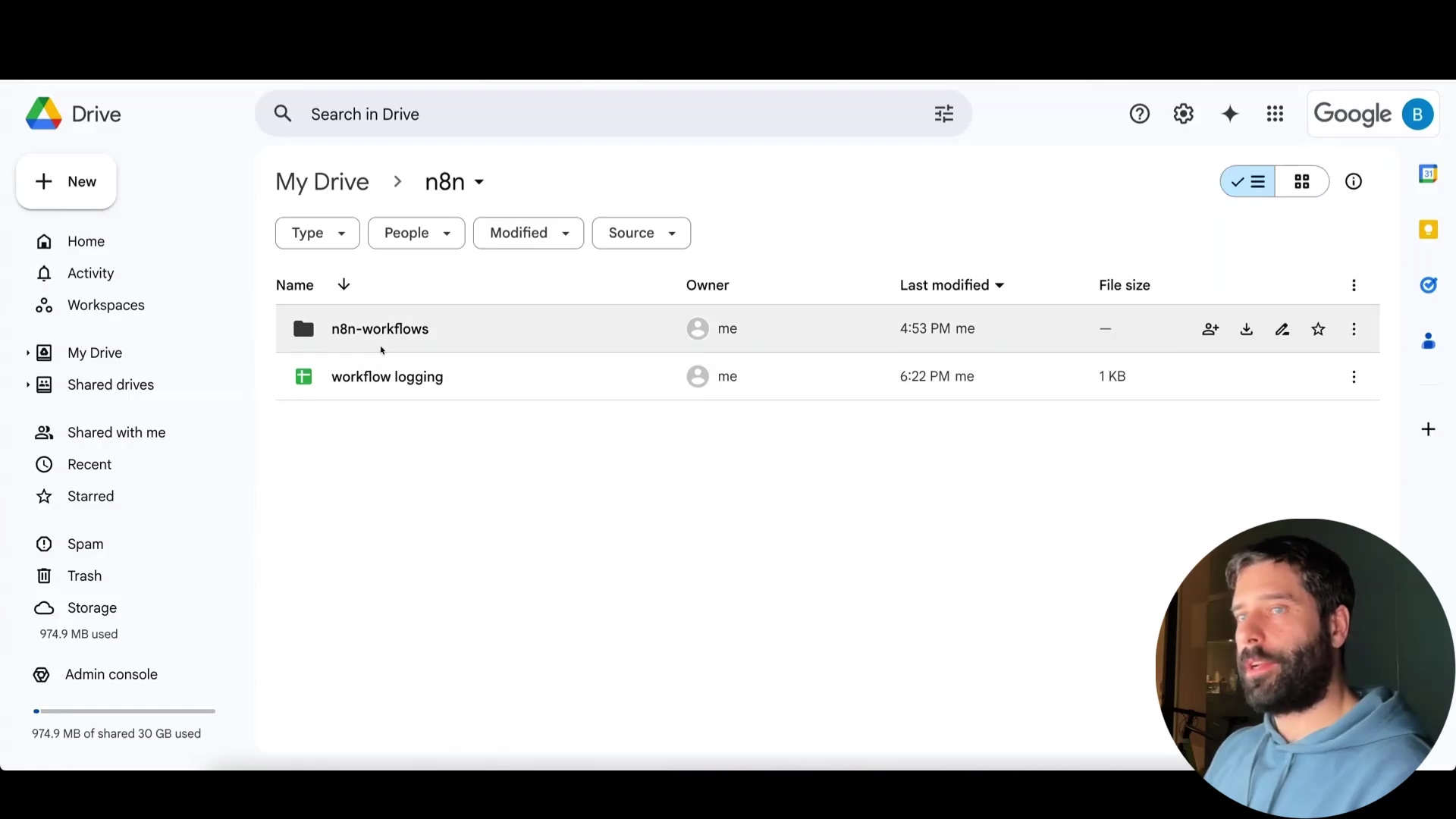 The image shows a Google Drive interface, specifically displaying the contents of the 'n8n' folder within 'My Drive'. Two items are listed: a folder named 'n8n-workflows' and a Google Sheet named 'workflow logging'. The 'workflow logging' sheet is shown with a 'Last modified' timestamp of '6:22 PM' and a file size of '1 KB'. The interface includes navigation elements on the left such as 'New', 'Home', 'My Drive', and 'Shared drives'. A man with a beard is visible in the bottom right corner, looking towards the left side of the screen. The overall interface is clean and follows Google Drive's design.