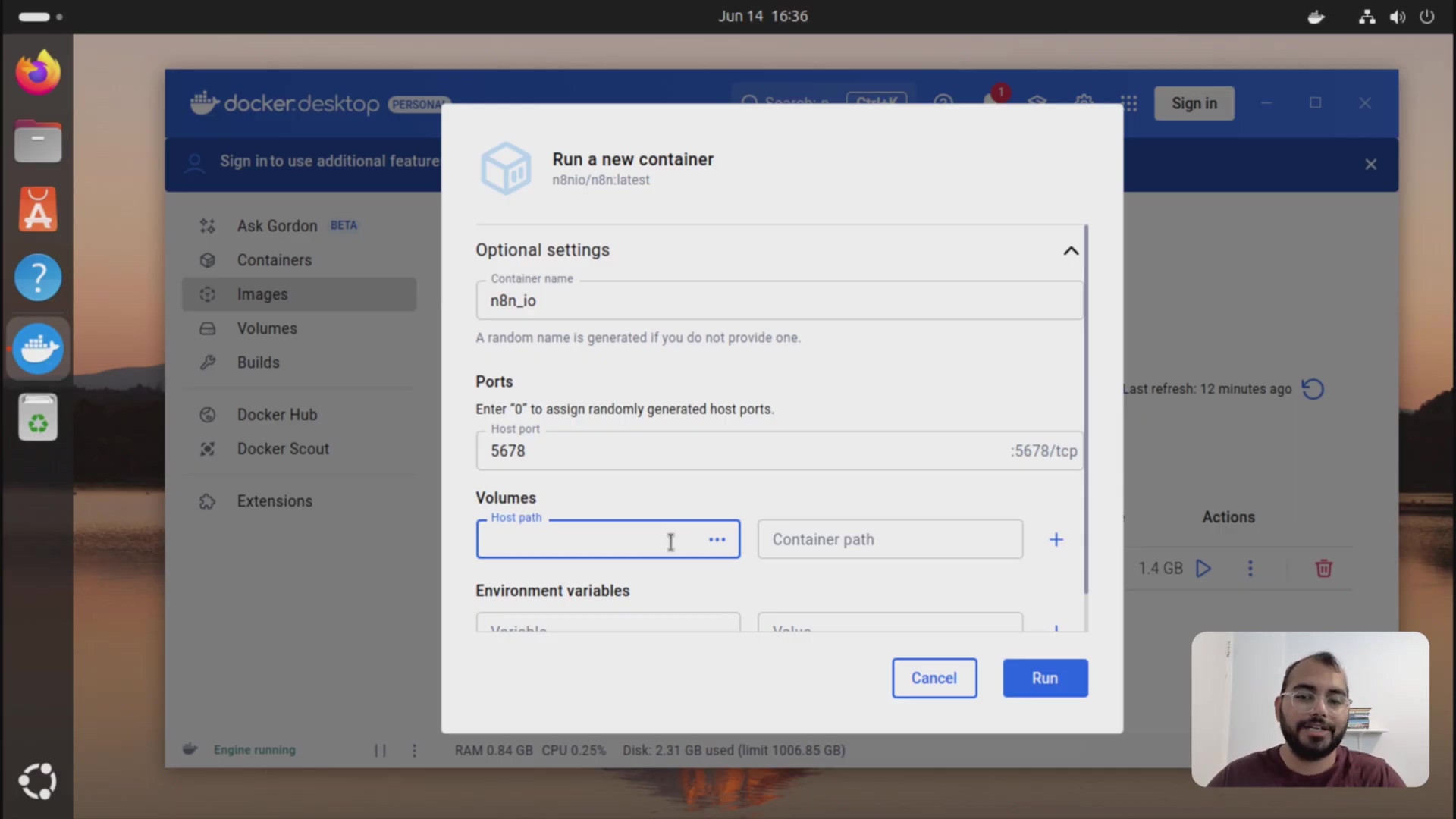 The image displays a 'Run a new container' dialog box within Docker Desktop. The dialog is titled 'n8n.io/n8n:latest'. It features an 'Optional settings' section where the user can configure the container. Fields include 'Container name' (pre-filled with 'n8n_io'), 'Ports' (with 'Host port' 5678 and '-5678/tcp'), and 'Volumes'. The 'Volumes' section has input fields for 'Host path' and 'Container path', with the 'Host path' field currently empty and highlighted, indicating user input is expected. Below the input fields, there are 'Environment variables' settings. At the bottom of the dialog, 'Cancel' and 'Run' buttons are visible. A person is visible in the bottom right corner of the screen.