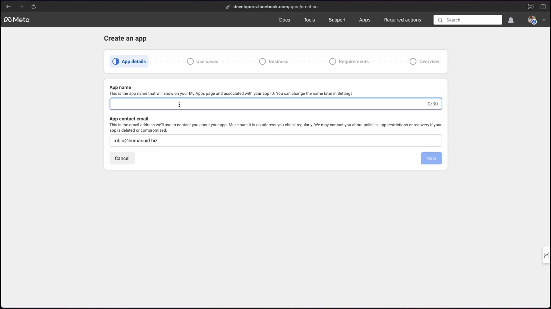 The image shows a web interface for creating a new application within the Meta Developer platform. The page is titled 'Create an app' and features a progress bar at the top with steps: 'App details', 'Use cases', 'Business', 'Requirements', and 'Overview'. The 'App details' step is currently selected. The main section of the page contains two input fields: 'App name' and 'App contact email'. The 'App name' field has a character counter '0/30' and a description stating, 'This is the app name that will show on your My Apps page and associated with your app ID. You can change the name later in Settings.' The 'App contact email' field is pre-filled with 'robin@humanoid.biz'. Below these fields are 'Cancel' and 'Next' buttons.