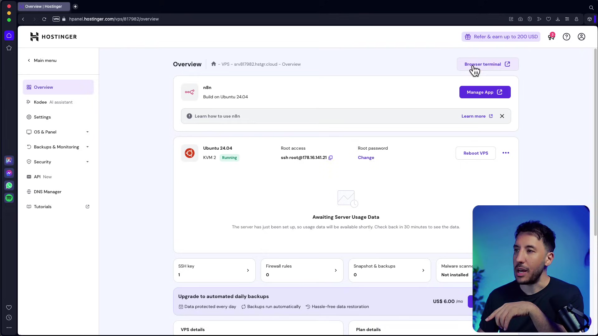 The image shows the Hostinger VPS management dashboard, specifically the 'Overview' section. The main panel displays information about the n8n application, indicating it's "Build on Ubuntu 24.04" and has a "Manage App" button. There's also a link to "Learn how to use n8n." Below this, details about the VPS are shown, including "Ubuntu 24.04," "KVM 2" with a "Running" status, and "Root access" information (ssh.root@178.16.141.21). A "Reboot VPS" button is present. A section for "Awaiting Server Usage Data" indicates that data will be available in 30 minutes. Further down, there are summary cards for "SSH key," "Firewall rules," "Snapshot & backups," and "Malware scanning." The bottom left shows "Upgrade to automated daily backups" with a cost of "US$ 6.00 /mo." A man is visible in the bottom right corner of the screen, looking towards the interface.