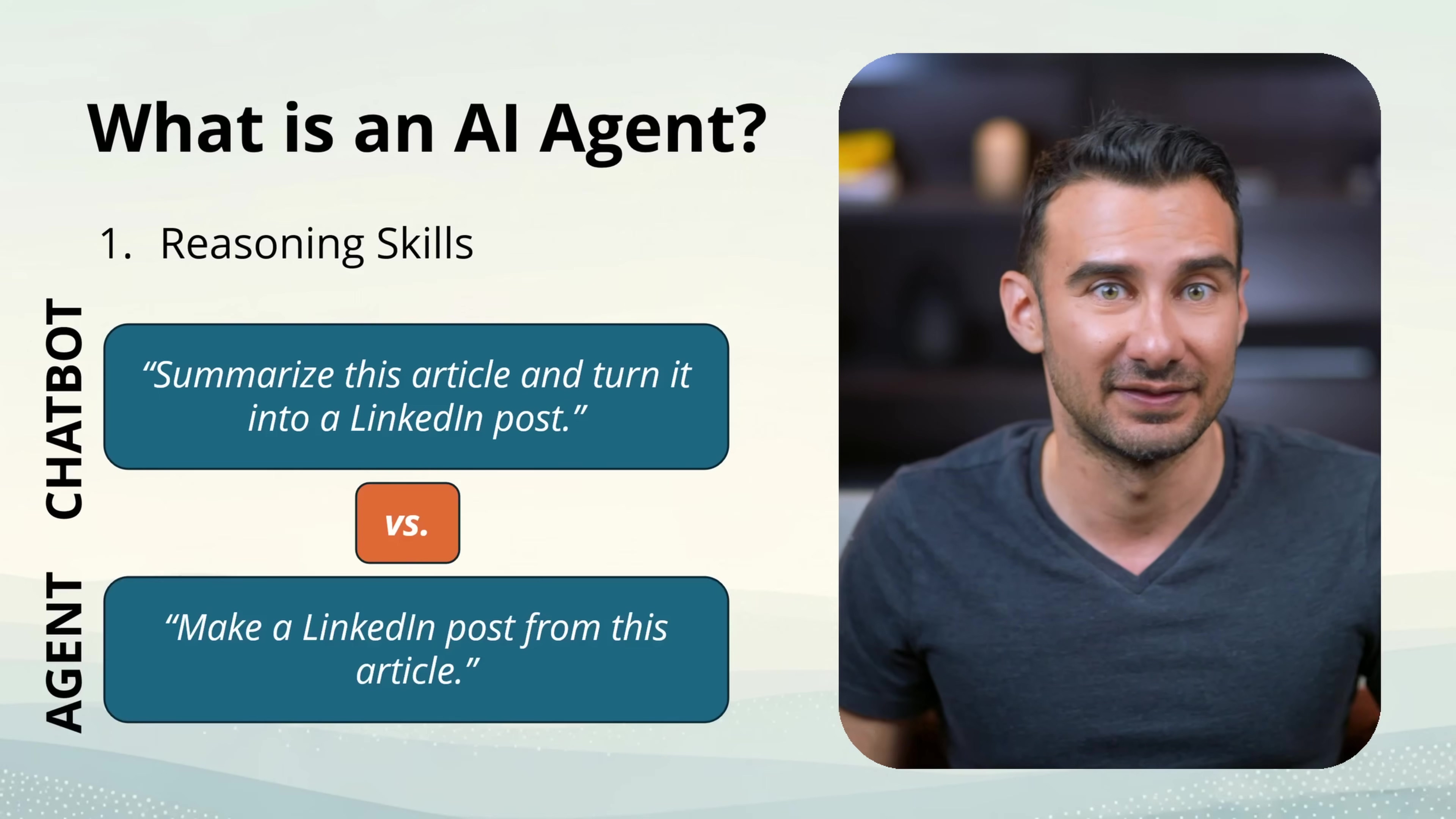 The image displays a slide titled "What is an AI Agent?" with a male presenter visible on the right side. The slide highlights "1. Reasoning Skills" as the first characteristic of an AI agent. Two text bubbles compare a "CHATBOT" and an "AGENT". The chatbot bubble says "Summarize this article and turn it into a LinkedIn post." The agent bubble, separated by an orange "vs." box, says "Make a LinkedIn post from this article." The presenter is a man with short dark hair and a dark grey t-shirt, looking slightly to the right with a neutral expression. The background is a light blue and white gradient with a subtle pattern.