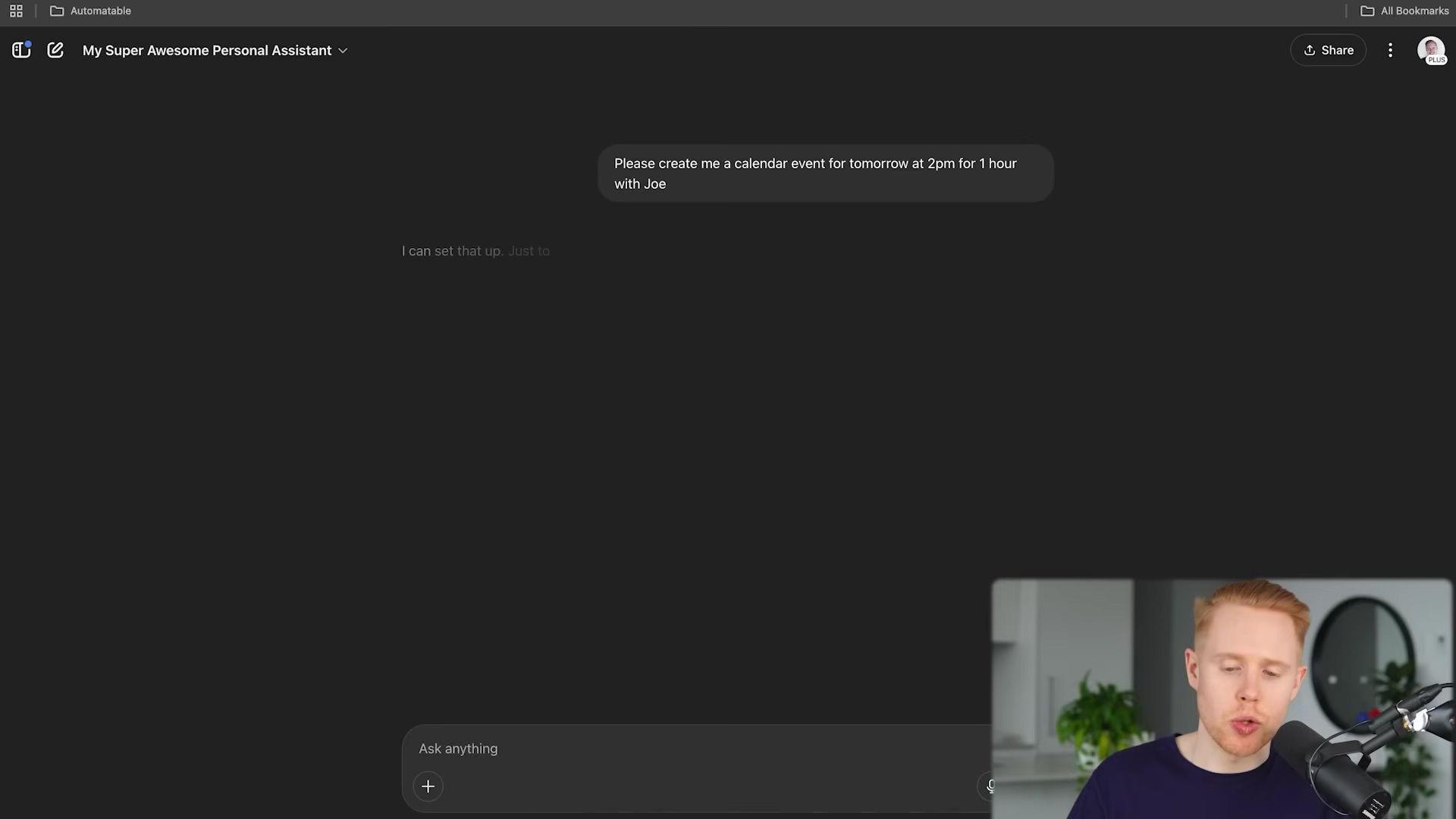 The image shows a dark-themed chat interface, likely a personal AI assistant, with a user's query and the AI's response. The top left corner displays 'Automatable' and 'My Super Awesome Personal Assistant'. A chat bubble from the user states, 'Please create me a calendar event for tomorrow at 2pm for 1 hour with Joe'. Below it, a greyed-out AI response says, 'I can set that up. Just to'. At the bottom, there's an input field labeled 'Ask anything' with a plus icon and a send button. A person with red hair and a microphone is visible in the bottom right corner, suggesting a video call or recording setup.
