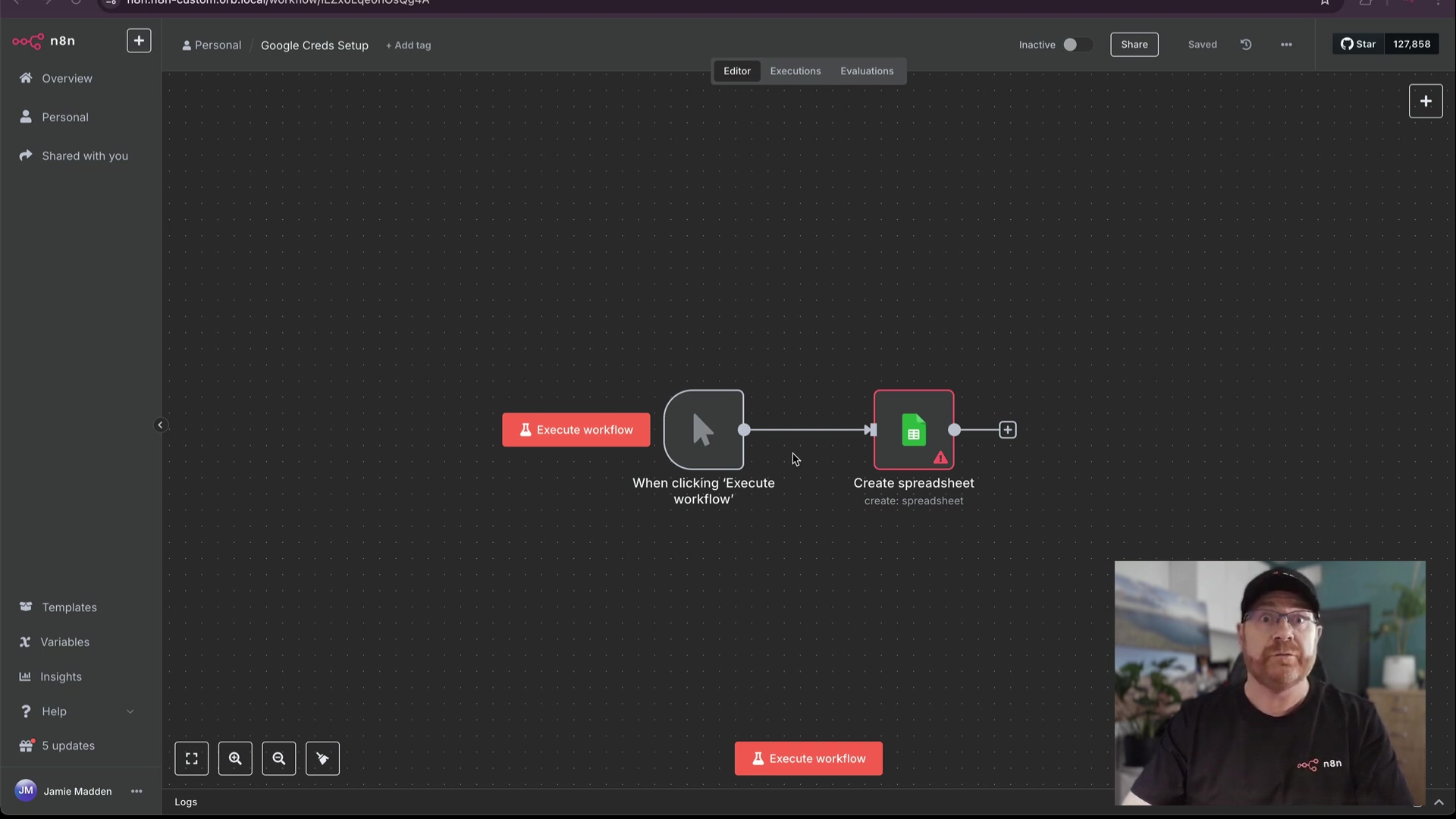 The image displays the n8n workflow editor interface. On the left, a vertical navigation bar shows options like 'Overview', 'Personal', 'Shared with you', 'Templates', 'Variables', 'Insights', 'Help', and 'Logs', with a '5 updates' notification. The main canvas shows a workflow with three connected nodes: 'Execute workflow', an intermediate node labeled 'When clicking 'Execute workflow'', and 'Create spreadsheet' which has an error icon. A plus icon is visible for adding new nodes. At the top, a horizontal bar features 'Personal', 'Google Creds Setup', '+ Add tag', 'Inactive', 'Share', 'Saved', a GitHub star count of '127,858', and a profile icon. A man with glasses and a black cap is visible in the bottom right corner, wearing a black t-shirt with a white logo. The overall color scheme is dark gray with white and red accents.