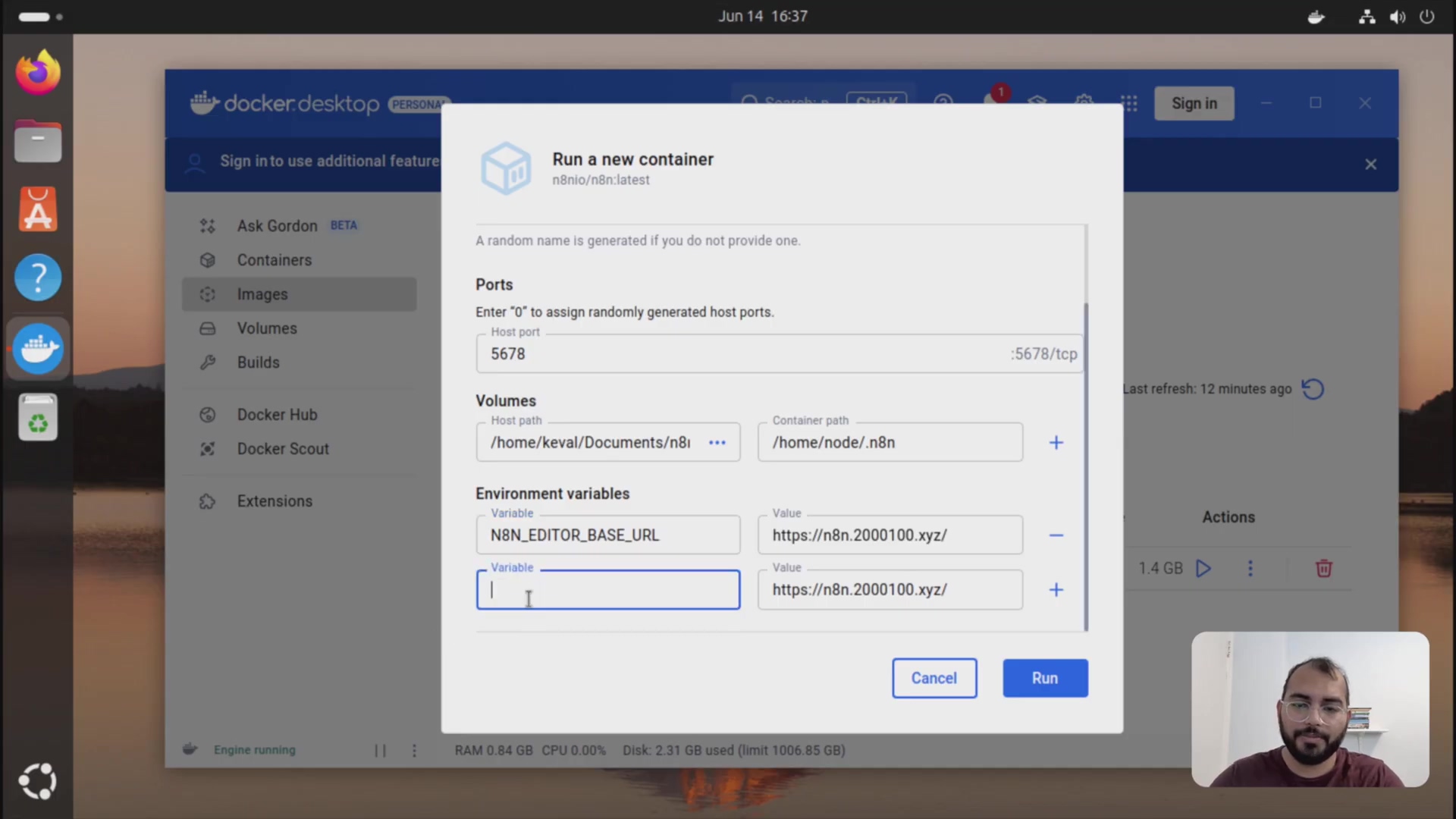 The image shows the 'Run a new container' dialog within Docker Desktop, similar to the previous image, but with additional fields populated. The 'Volumes' section now shows '/home/Keval/Documents/n8n-data' as the 'Host path' and '/home/node/.n8n' as the 'Container path'. Below this, the 'Environment variables' section has an entry for 'N8N_EDITOR_BASE_URL' with the value 'https://n8n.2000100.xyz/'. There is an empty 'Variable' input field below this. The 'Cancel' and 'Run' buttons are at the bottom of the dialog. A person is visible in the bottom right corner of the screen.