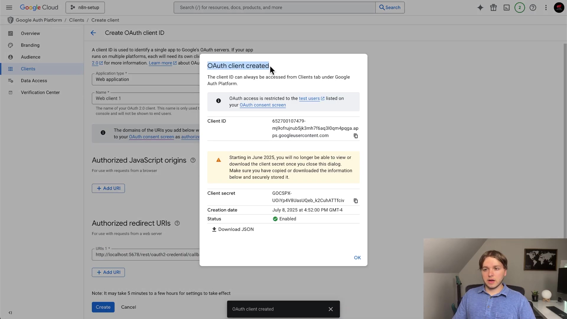 The image shows a pop-up window titled 'OAuth client created' over the Google Cloud Platform interface. This pop-up displays the 'Client ID' and 'Client secret' for a newly created OAuth client. The Client ID is '652700107479-mpo1ruyu5b3mh76aq30mq4pqa.apps.googleusercontent.com' and the Client secret is 'GOCSPX-UOIYgV4B8aeU0eb_X2CuHAT1fcv'. There's a warning message about the client secret no longer being viewable after closing the dialog and advising to download or copy it. The creation date is listed as 'July 8, 2025 at 4:52:00 PM GMT-4' and the status is 'Enabled'. A button labeled 'OK' is present at the bottom of the pop-up. The background interface shows a 'Create OAuth client ID' form with fields for 'Application type', 'Name', 'Authorized JavaScript origins', and 'Authorized redirect URIs'. A person is visible in the bottom right corner of the screen.