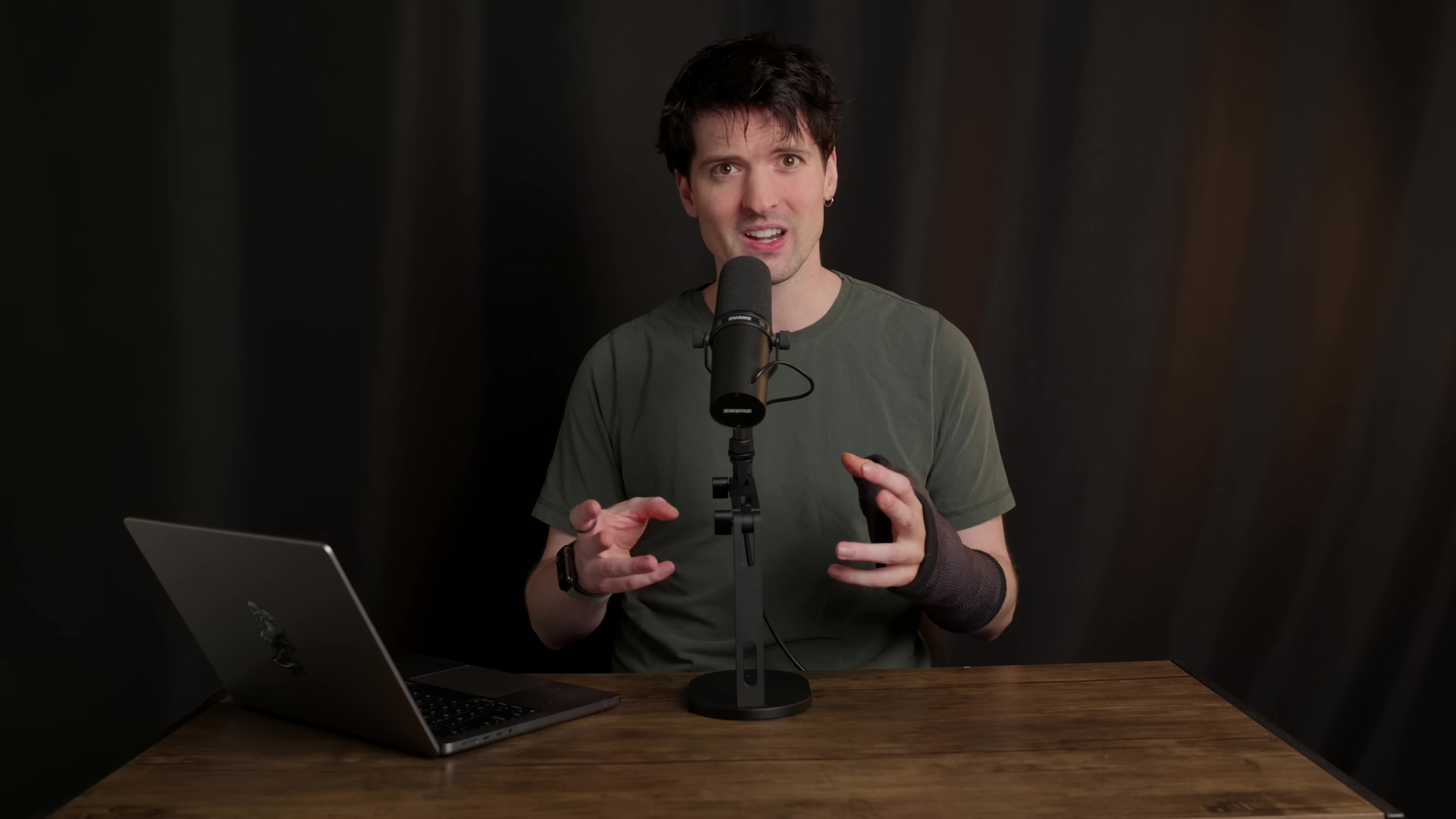 Man speaking into microphone, gesturing with both hands
