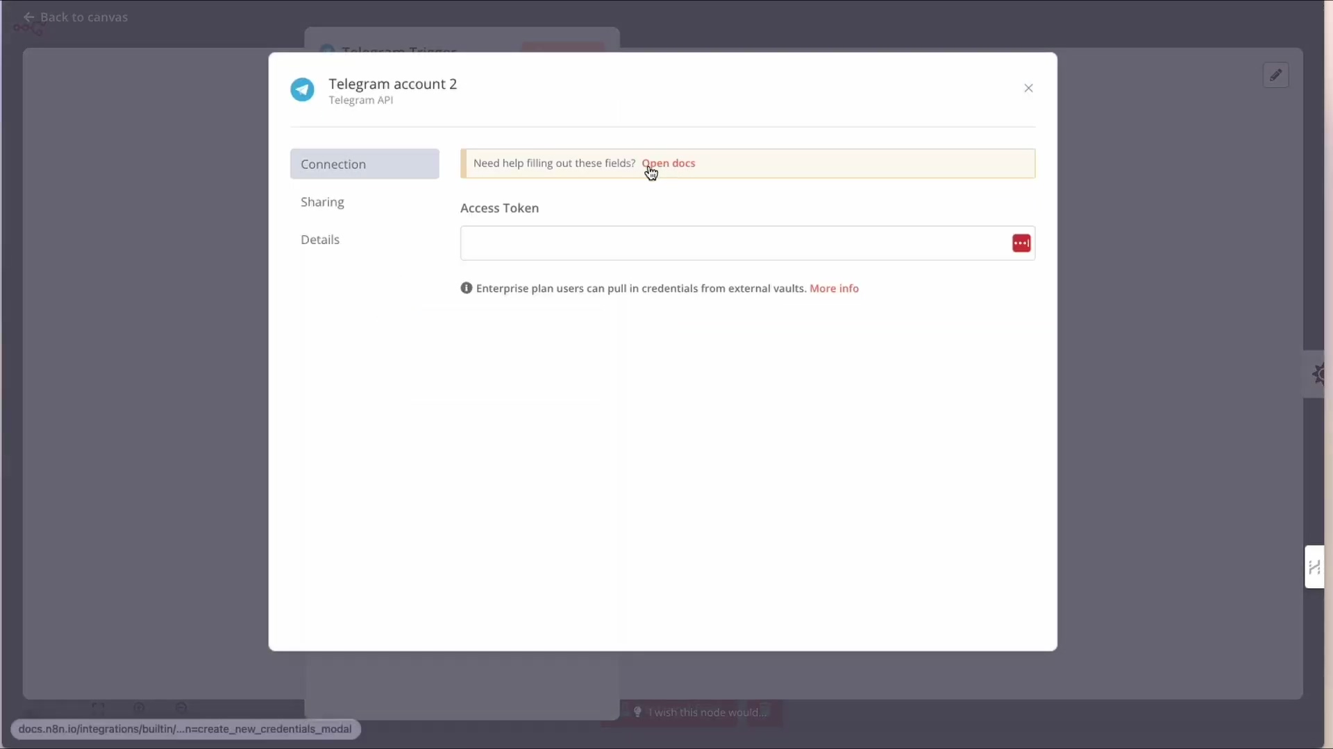 The image displays a modal window in the n8n interface titled 'Telegram account 2' with 'Telegram API' below it. The modal is for setting up a new Telegram credential. It has three tabs: 'Connection', 'Sharing', and 'Details'. The 'Connection' tab is currently active. A yellow banner at the top of the content area asks, 'Need help filling out these fields?' with a clickable 'Open docs' link. Below this, there's an input field labeled 'Access Token' which is currently empty, indicated by a red outline and a small red square icon, suggesting it's a required field. A small information icon is next to the label, and a red ellipsis icon is next to the input field. At the bottom, there's a note: 'Enterprise plan users can pull in credentials from external vaults. More info'. The background shows a blurred n8n workflow editor.