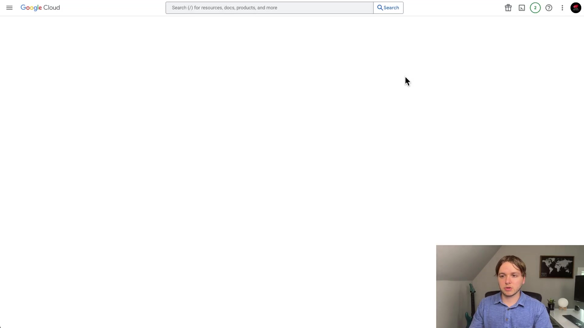 The image shows a web browser window displaying the Google Cloud console. The main content area is mostly white and empty, indicating a loading state or a blank page. At the top, there's a search bar labeled 'Search (/) for resources, docs, products, and more' with a search icon. On the left, a hamburger menu icon is visible. On the right, there are icons for a trash can, a bell, a question mark, and a user profile picture. The man from previous frames is visible in the bottom right corner, looking at the screen.