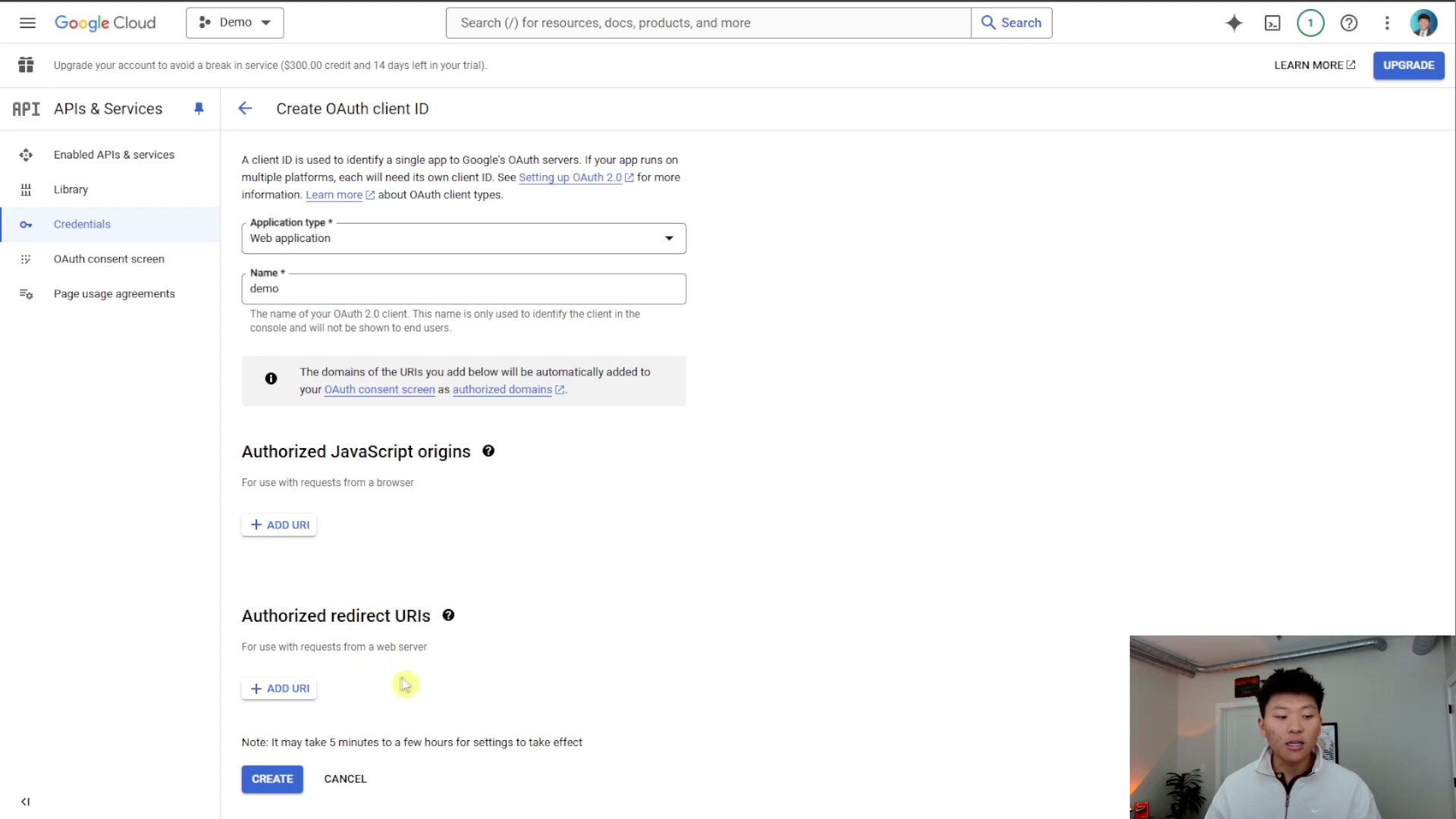 The image displays the Google Cloud console interface for creating an OAuth client ID. The main content area shows sections for 'Application type' (set to 'Web application'), 'Name' (set to 'demo'), 'Authorized JavaScript origins', and 'Authorized redirect URIs'. Below these sections are 'CREATE' and 'CANCEL' buttons. A note at the bottom states, 'Note: It may take 5 minutes to a few hours for settings to take effect'. A person is visible in the bottom right corner, looking at the screen.