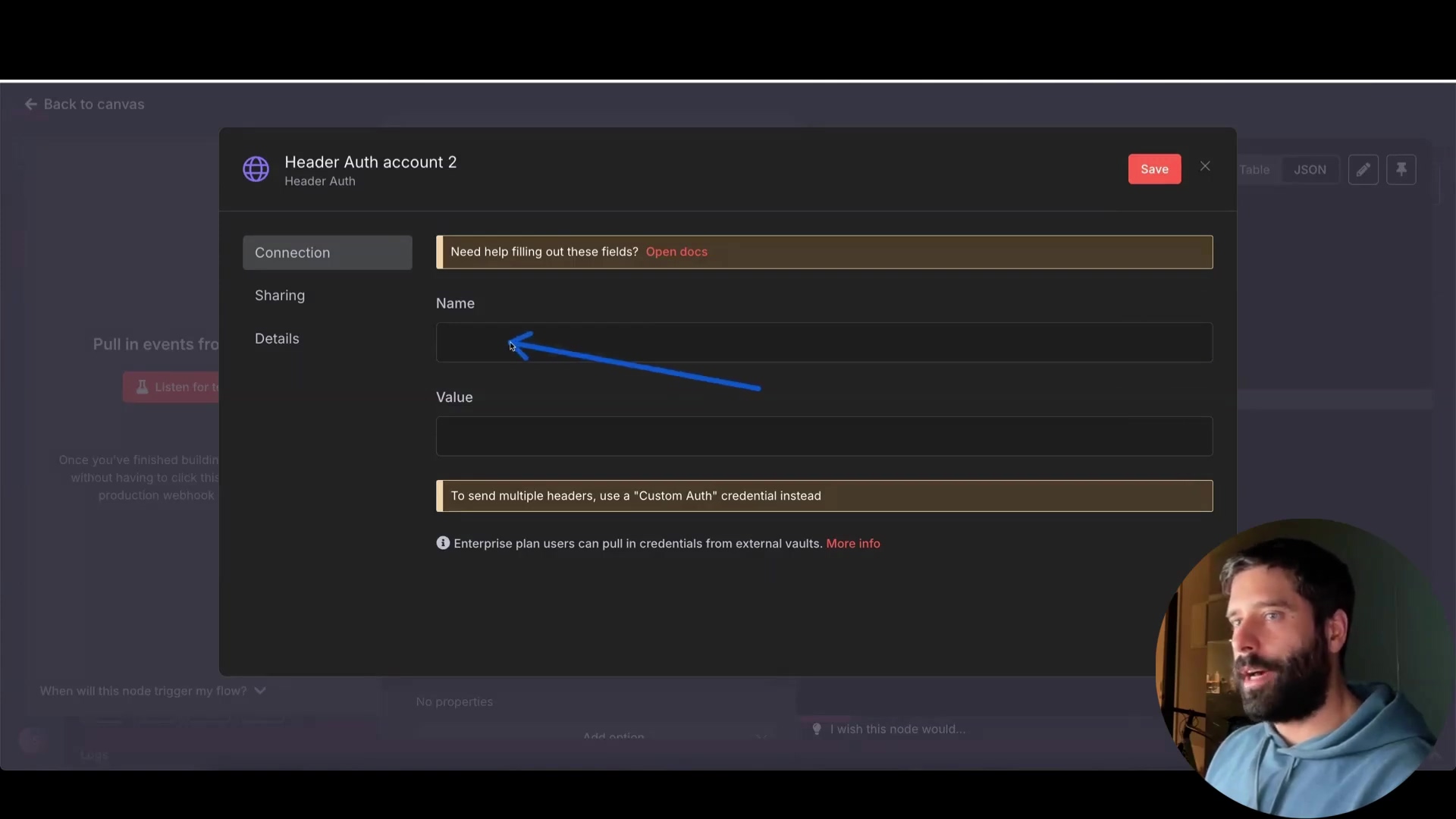 The image shows a dark-themed software interface, likely an n8n workflow editor, with a modal window titled "Header Auth account 2". The modal has tabs for "Connection" and "Sharing", with "Connection" currently selected. Below the tabs, there are input fields labeled "Name" and "Value" for header authentication details. A small text box below the "Value" field advises: "To send multiple headers, use a 'Custom Auth' credential instead." Further down, an information icon is followed by text: "Enterprise plan users can pull in credentials from external vaults. More info." A blue arrow points to the "Name" input field. On the top right of the modal, there are "Save", "Table", and "JSON" buttons, with "Save" highlighted in red. The background shows a partially visible workflow canvas with text like "Pull in events from" and "Listen for a". A man is visible on the bottom right, looking towards the screen.