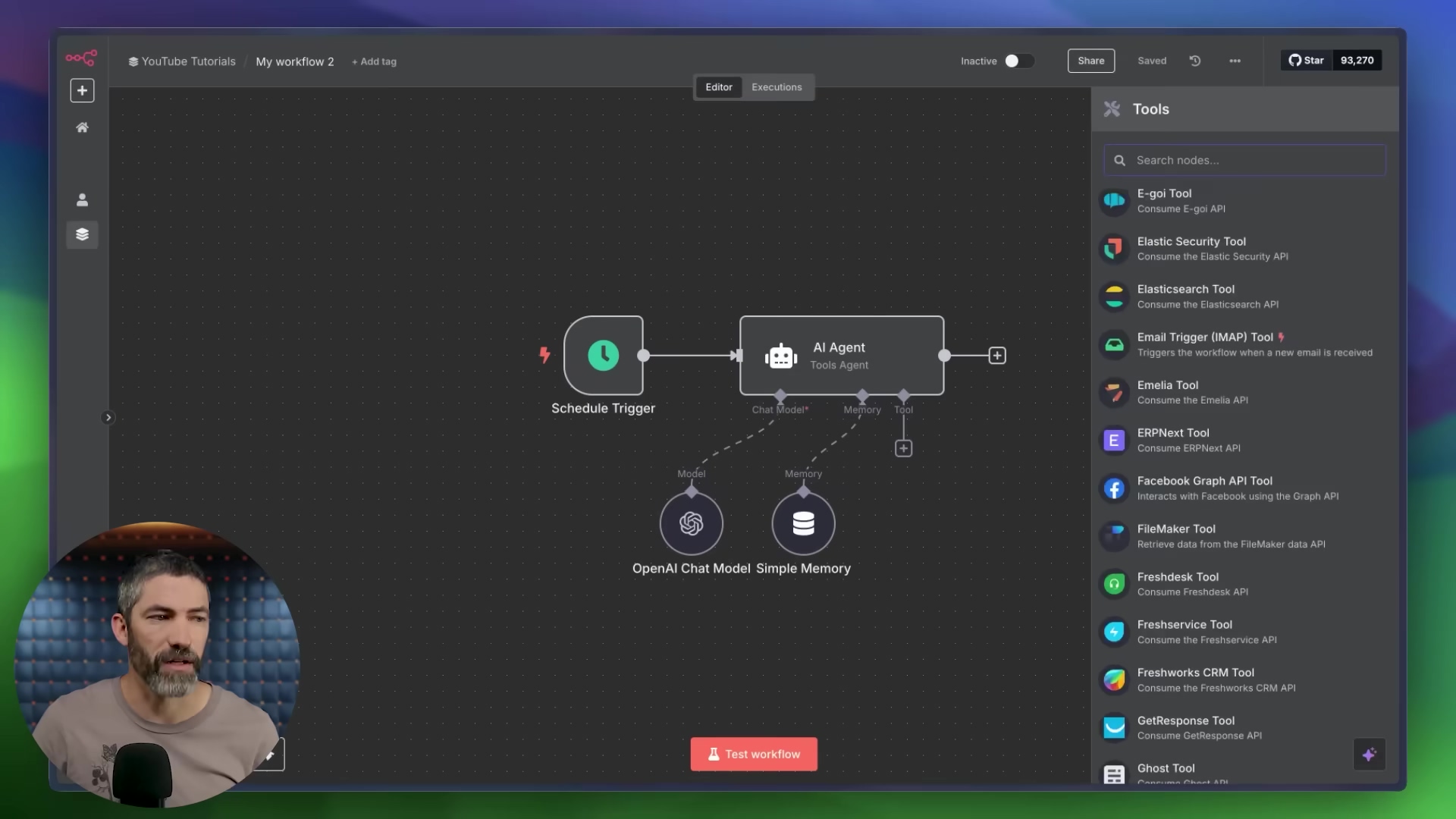 The image shows a split view. On the left, a man with a beard is visible from the chest up, looking towards the right side of the frame. He is wearing a light brown t-shirt. On the right, a software interface is displayed, featuring a dark theme with a workflow diagram in the center. The diagram includes nodes labeled 'Schedule Trigger', 'AI Agent (Tools Agent)', and 'OpenAI Chat Model Simple Memory', connected by lines. A sidebar on the right is open, titled 'Tools', with a search bar and a list of various tools like 'E-goi Tool', 'Elastic Security Tool', 'Elasticsearch Tool', 'Email Trigger (IMAP) Tool', 'Emelia Tool', 'ERPNext Tool', 'Facebook Graph API Tool', 'FileMaker Tool', 'Freshdesk Tool', 'Freshservice CRM Tool', 'GetResponse Tool', and 'Ghost Tool'. The top bar of the interface shows 'YouTube Tutorials', 'My workflow 2', '+ Add tag', 'Editor', 'Executions', 'Inactive', 'Share', 'Saved', and a star icon with '93,270'. At the bottom of the interface, a red button reads 'Test workflow'.