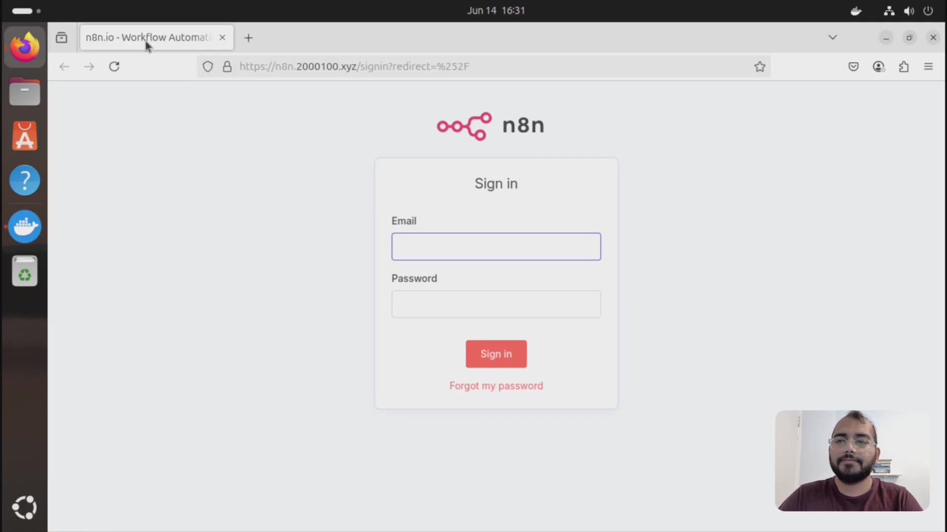 The image displays a web browser window showing the n8n login interface. The browser's address bar shows 'n8n.io - Workflow Automation' as the tab title and 'https://n8n.2000100.xyz/signin?redirect=%2F' as the URL. The main content area features a white card with 'Sign in' as the title, followed by input fields for 'Email' and 'Password', a red 'Sign in' button, and a 'Forgot my password' link. The n8n logo, which consists of a stylized 'n8n' text with a connected-nodes icon, is visible above the 'Sign in' title. A person with a beard and glasses is visible in the bottom right corner of the screen, partially obscured by the browser window. The desktop background appears to be a dark, abstract image.