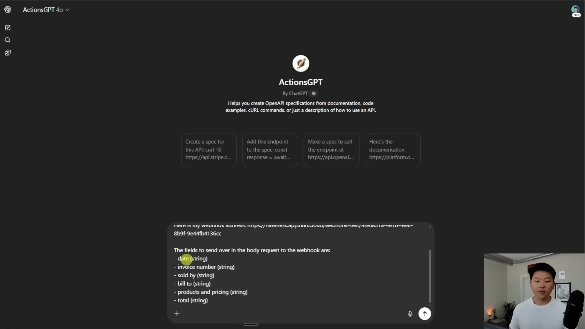 The image displays a split view of a computer screen, with a man in a black t-shirt visible in the bottom right corner. The left side of the screen shows the 'ActionsGPT' interface, a tool by ChatGPT, designed to help create OpenAPI specifications. The main area of the interface is dark gray with white text. At the top, there's a title 'ActionsGPT' and a description 'Helps you create OpenAPI specifications from documentation, code examples, cURL commands, or just a description of how to use an API.' Below this, there are four large buttons: 'Create a spec for this API.curl -S', 'Add this endpoint to the spec: const response = await...', 'Make a spec to call the endpoint at https://api.openai...', and 'Here's the documentation: https://platform.o...'. A chat input field is at the bottom, showing a prompt and a response. The response lists parameters for a webhook request body: 'date (string)', 'invoice number (string)', 'sold by (string)', 'bill to (string)', 'products and pricing (string)', and 'total (string)'. The man is looking towards the screen, gesturing with his right hand.